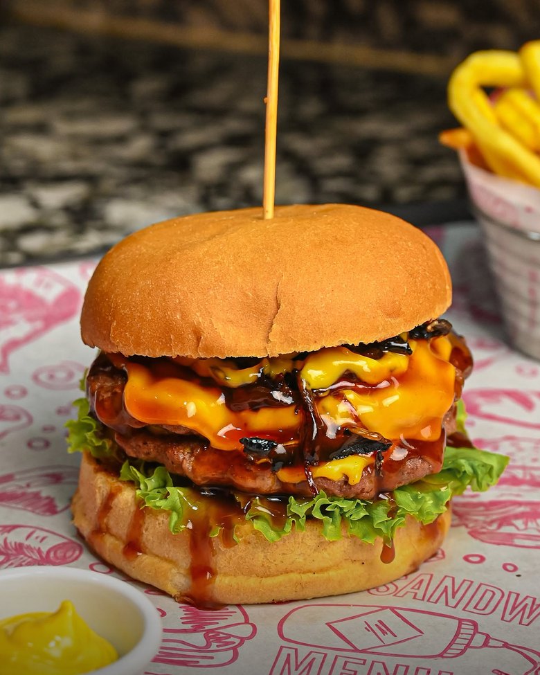 Burger double au cheddar fondu et sauce barbecue, servi avec des frites